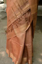 Load image into Gallery viewer, Folded view of light brown Sambalpuri tussar silk saree by Pasapali with visible chevron zari border and golden tissue pallu
