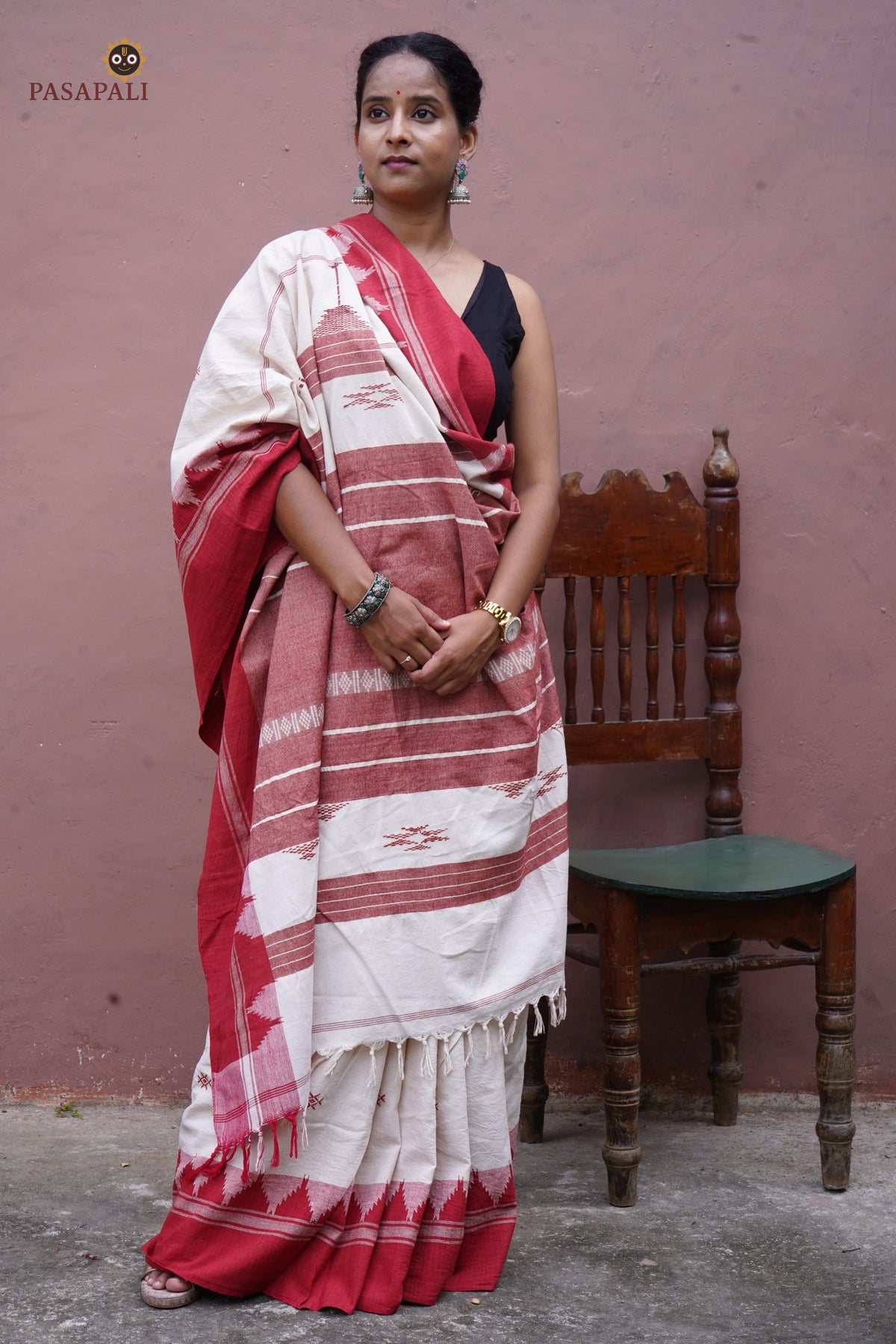 Bhoomi Kotpad natural dye saree folded flat — off-white with red kumbha border and tribal motif detail visible