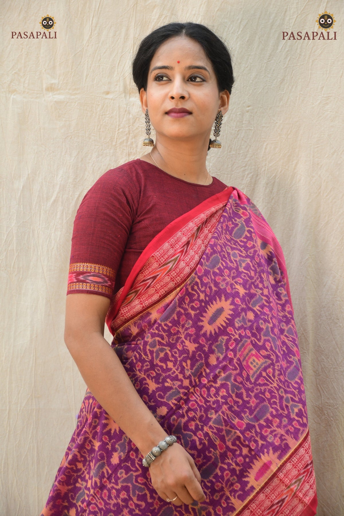Janapadi Sambalpuri Bandha saree front drape — purple mercerized cotton with red accents and tribal body motifs.