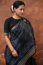 Load image into Gallery viewer, Front drape of Krishnakali black Sambalpuri cotton saree by Pasapali — tribal body motifs and fish motif border visible

