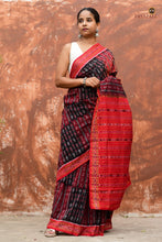 Load image into Gallery viewer, Tilottama Black Sambalpuri handloom saree folded — red pallu visible, ikat stripe border, 5.40 metre GI certified cotton saree
