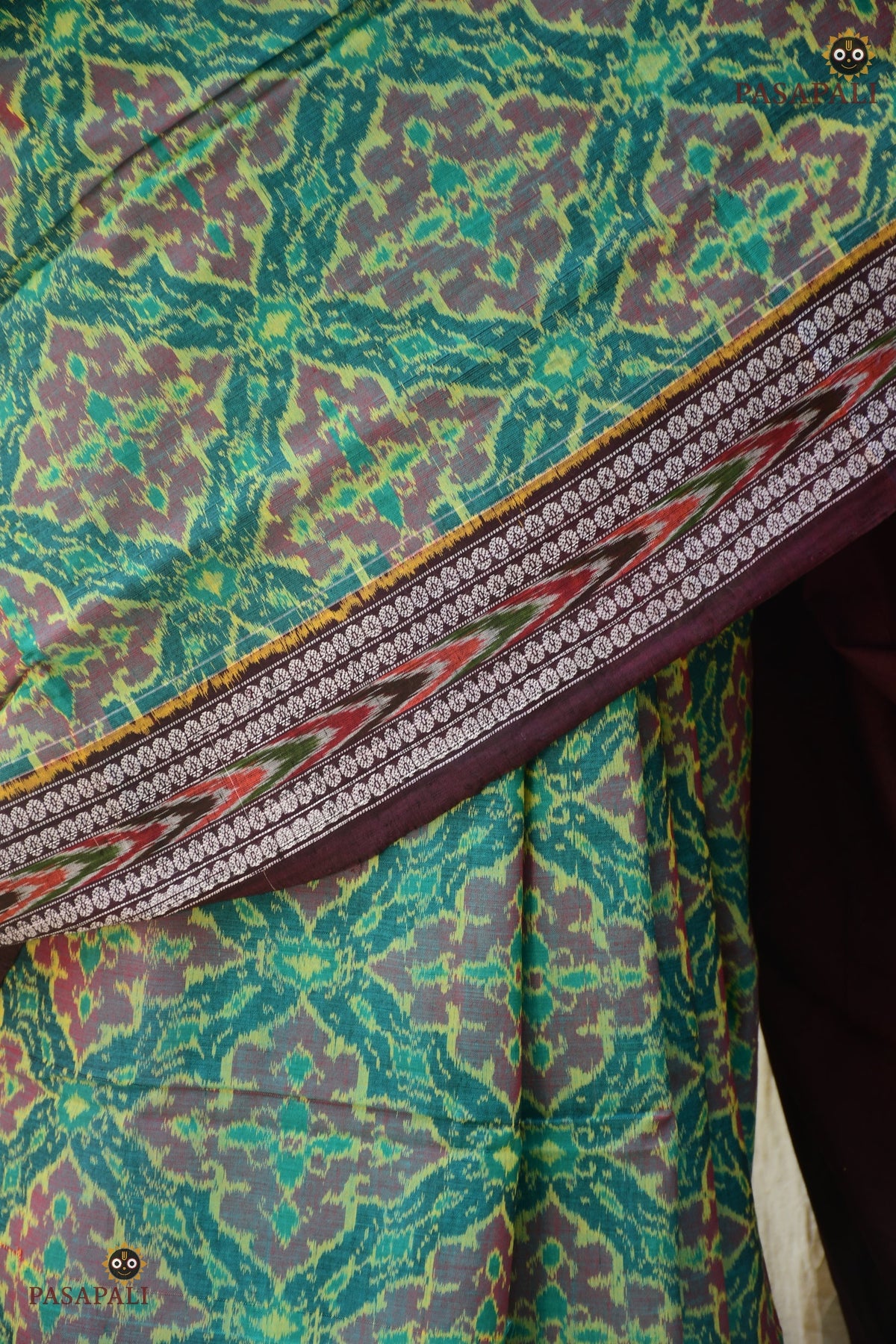 Flat lay of Vanalata green Sambalpuri cotton saree — Plula body, Rudraksha border, Pasapali Bandha handloom